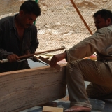 096   Head shipwright drills holes on a plank using a traditional bow drill