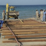 044   A digger drags completed sections of track down the beach