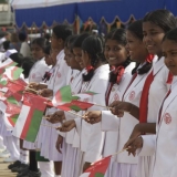 052   Local school children wave Omani flags in welcome.