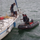 113   Drenched by rain, crew members work to pull the drifting sailboat away