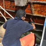 051   Fahad Al Shaibi applies another protective coat of fish oil to the hull in preparation for the final leg to Singapore